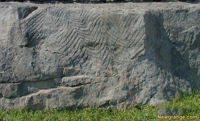 Close-up of Newgrange Kerbstone K93 with rows of chevron and zigzag carvings across the grey stone face.