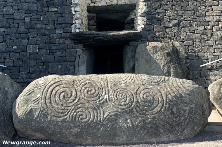 Kerbstone 1 with triple spirals and lozenges before the Newgrange entrance and roofbox opening.